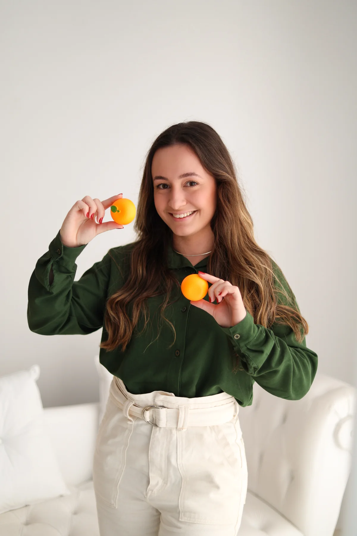 Laura sorrindo, segurando frutas perto do rosto.